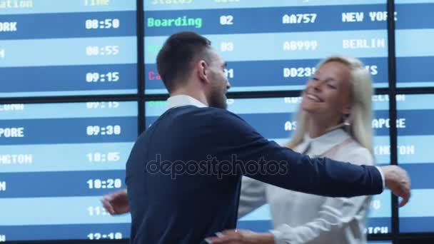 Riunione uomo e donna nella sala arrivi dell'aeroporto accanto all'ufficio informazioni. Le persone si abbracciano e sorridono . — Video Stock