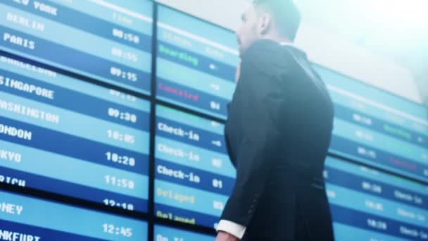 Homme d'affaires parlant sur téléphone portable tout en regardant le panneau d'information à l'aéroport . — Video
