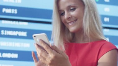 Çekici gülümseyen sarışın kadın kullanarak cep telefonu bilgi kurulu Havaalanı yanındaki.