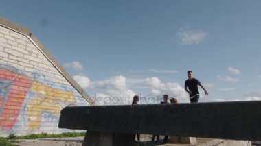 Genç erkek Freerunner hileler ve açık havada kentsel ortamda atlar.