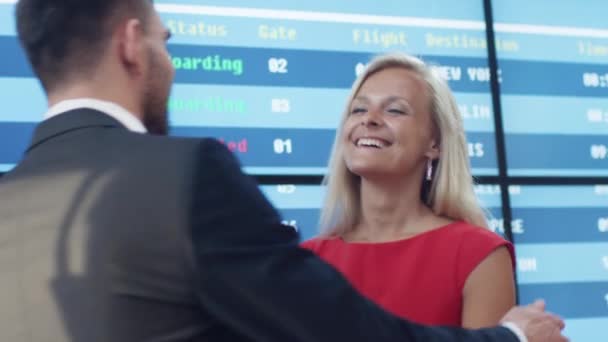 Mann und Frau treffen sich in der Ankunftshalle des Flughafens. Menschen umarmen sich und lächeln. — Stockvideo
