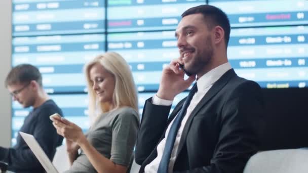 Zakenman praten aan de telefoon terwijl Boarding wachten bij vertreklounge op de luchthaven. — Stockvideo