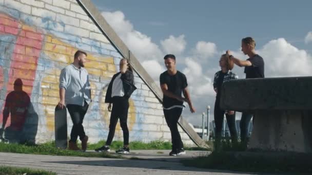 Joven Masculino Freerunner Realizar trucos y saltos abeto sus amigos adolescentes al aire libre en el entorno urbano . — Vídeos de Stock