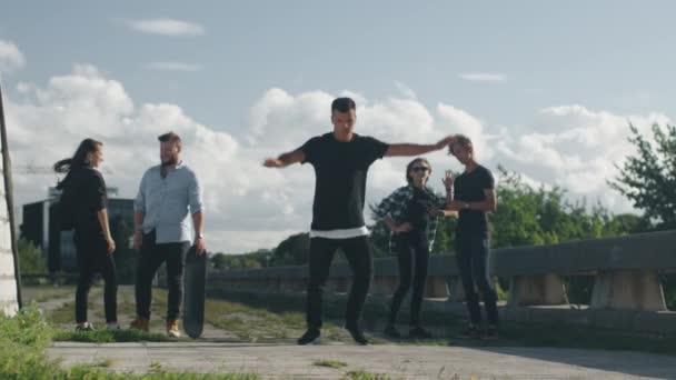 Jovem Freerunner masculino realizando truques e saltos abeto seus amigos adolescentes ao ar livre em ambiente urbano . — Vídeo de Stock