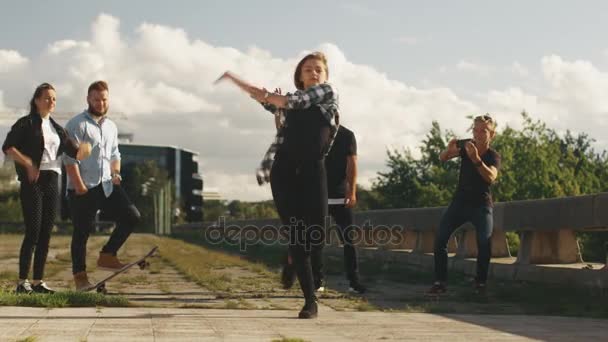Menina adolescente realizando dança moderna para grupo de amigos ao ar livre em ambiente urbano . — Vídeo de Stock