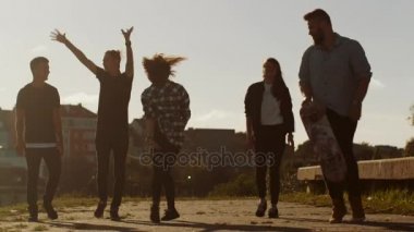 Gülüyor, eller, kameraya doğru ileri hareket ederken atlama Raising Mutlu genç grup.