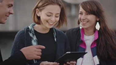 Grup gülen ve kentsel çevre mekanlarda eğlence için Tablet bilgisayarı kullanan gençler gülüyor.