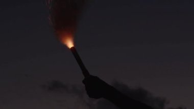 Bir Holding ve sallayarak kırmızı sinyal Flare yürüyüş ileri doğru kamera gece ciddi genç grup.