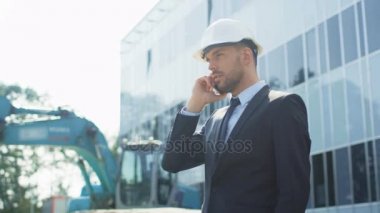 Baret inşaat alanında telefonda konuşurken, işadamı.