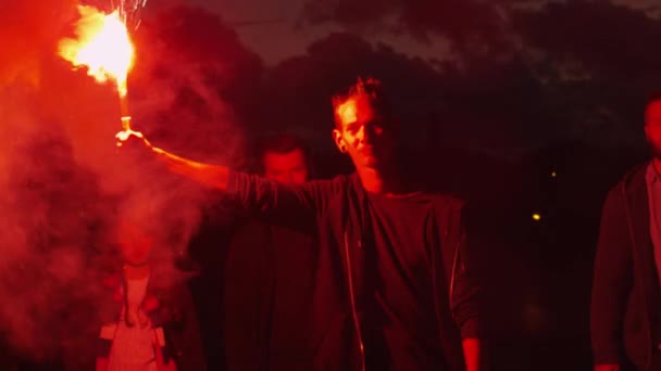 Group of Serious Teenagers with one Holding and Waving Red Signal Flare Walking Forward Towards Camera at Night. — Stock Video