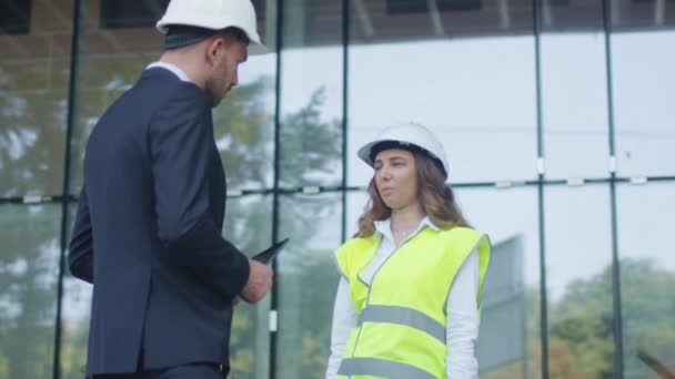 Biznesmen i kobiece inżynier w twardym kapelusze o uzgadnianie umowy na placu budowy. — Wideo stockowe