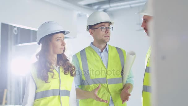 Team av ingenjörer i hårda hattar har konversation inne i byggnad Under uppförande. — Stockvideo