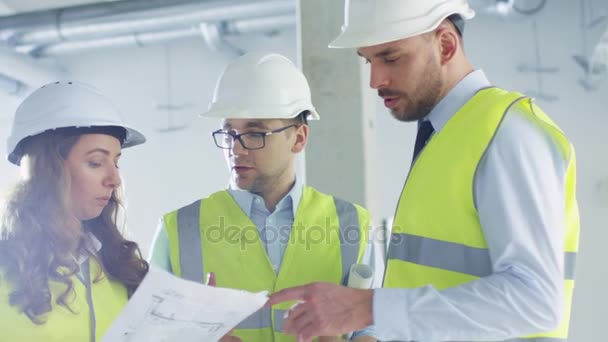 Tým inženýrů v Belfastu konverzaci, při pohledu na modrotisk, uvnitř budovy ve výstavbě. — Stock video