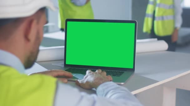 Μηχανικός χρησιμοποιώντας φορητό υπολογιστή με πράσινη οθόνη στο εσωτερικό του κτιρίου υπό κατασκευή. Μεγάλη για χρήση Mockup. — Αρχείο Βίντεο