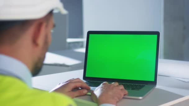 Ingeniero que utiliza ordenador portátil con pantalla verde dentro del edificio en construcción. Ideal para el uso de burla . — Vídeos de Stock