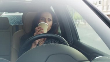 Çekici gülümseyen iş kadın sürme bir araba sabahın erken saatlerinde. Kahve içme.