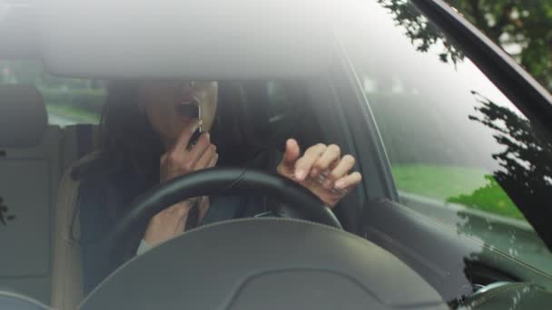 Привлекательная улыбающаяся деловая женщина, наносящая макияж в автомобиле — стоковое видео
