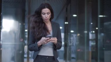 İş kadını iş bölgesine cep telefonu tutan sokaklarında yürüyüş. Ağır çekim