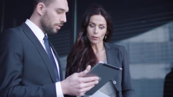 Hombre y mujer de negocios teniendo reunión y conversación al aire libre. Empresario sosteniendo y usando la tableta mientras habla . — Vídeo de stock