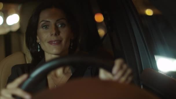 Приваблива усміхнена бізнес жінка водіння автомобіля ввечері — стокове відео