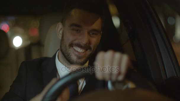 Feliz hombre de negocios sonriente realizando el gesto ganador mientras conduce un coche por la noche — Vídeo de stock