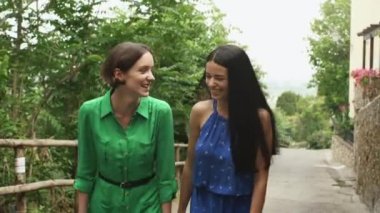 Hafif yaz aylarında iki çekici genç bayan elbise yürüyüş ve Avrupa şehir sokaklarında konuşuyor. İyi gününde, gülümseyen ve gülerek olduklarını