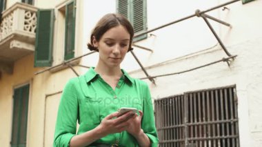 Avrupa şehir sokaklarında hafif yaz içinde çekici genç esmer kadın. O cep telefonu seyir ve istimal o.