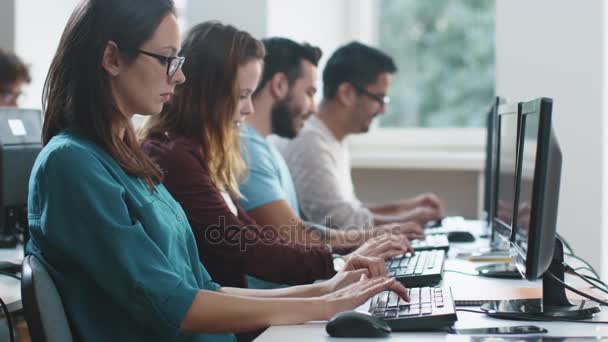 Gruppo di studenti di razza mista sono seduti in una fila in classe di computer e di lavoro — Video Stock