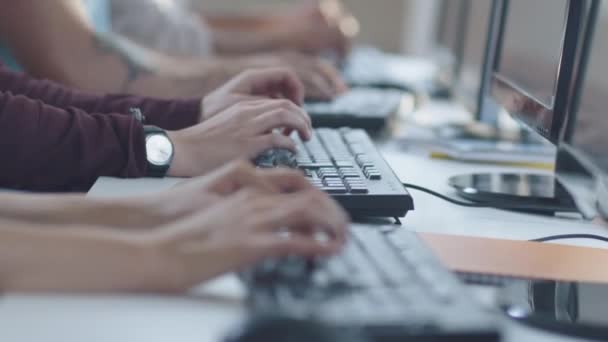 Junge Leute mit gemischter Rasse sitzen in einer Reihe und arbeiten an Computern. Tippen auf der Tastatur. — Stockvideo