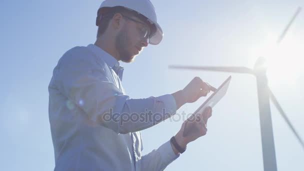 Jeune ingénieur utilisant un ordinateur tablette en plein air. Éoliennes en arrière-plan . — Video