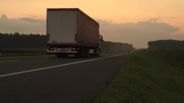 Vrachtwagen rijden op snelweg bij zonsondergang — Stockvideo