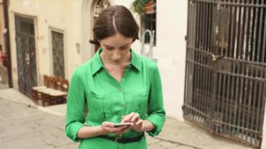 Avrupa şehir sokaklarında hafif yaz içinde çekici genç esmer kadın. O cep telefonu seyir ve istimal o.