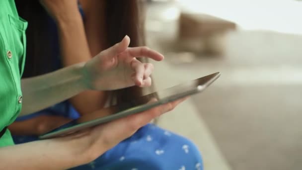 Deux jolies jeunes femmes dans des robes d'été lumière à l'aide d'un ordinateur tablette dans les rues de la ville européenne .