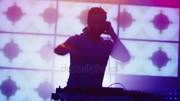 DJ retroiluminado tocando música en discoteca. Silueta de DJ. Animación brillante en el fondo . — Vídeos de Stock