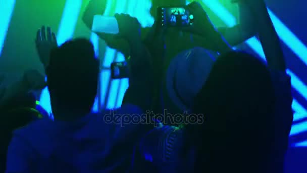DJ jouant de la musique dans une boîte de nuit, personnes dansant, enregistrement du concert avec des téléphones mobiles . — Video