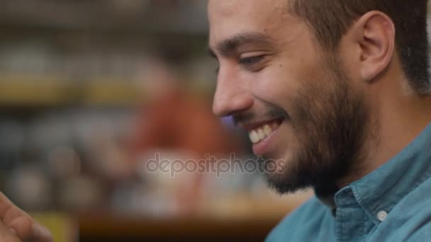 Hiszpanie etniczna młody człowiek przy użyciu telefonu komórkowego w przytulnej kawiarni. — Wideo stockowe
