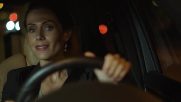 Привлекательная улыбчивая деловая женщина за рулем автомобиля на вечере — стоковое видео