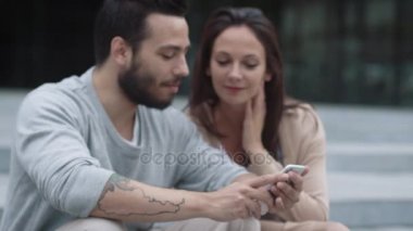 Genç pozitif kadın ve erkek misin kullanarak cep telefonu açık havada.
