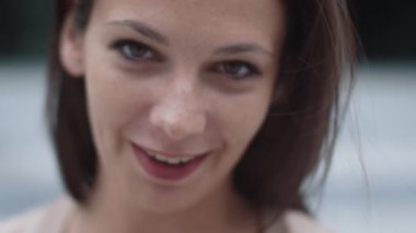 Kentsel ortamda çekici gülümseyen beyaz elbise genç kadın portresi.