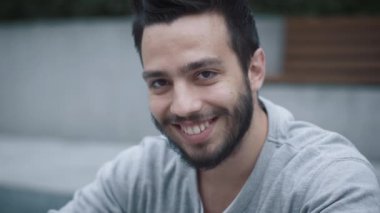 Kentsel ortamda çekici gülümseyen Latin asıllı etnik genç adam portresi.