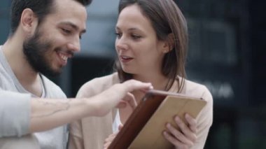 Genç adam ve basamaklarında oturan ve Tablet bilgisayarı kullanan kadın.