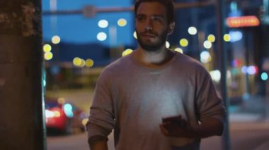 Çekici bir adam cep telefonuyla gece şehir sokakları.