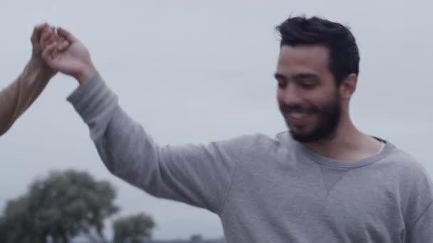 Feliz sonrisa atractiva pareja caminando y divirtiéndose al aire libre. Hombre sosteniendo su mano Ayudando a la mujer a mantener el equilibrio . — Vídeos de Stock