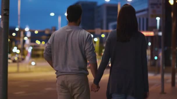 Ακολουθήστε το πλάνο του ελκυστική ευτυχισμένο ζευγάρι περπάτημα στους δρόμους της πόλης νύχτα — Αρχείο Βίντεο