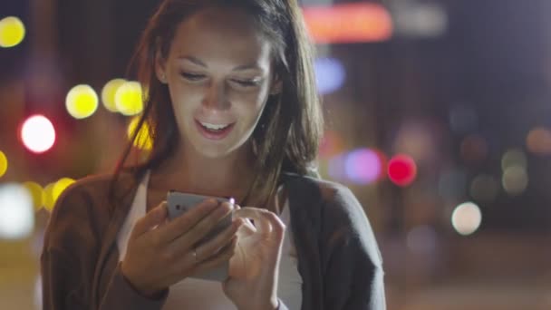 Donna attraente che utilizza il telefono cellulare durante la passeggiata per le strade di Night Town — Video Stock