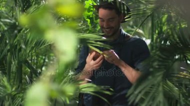 Maceracı cep telefonuyla orman ormanda şapkalı.