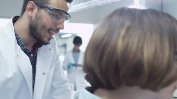 Team multiethnischer Studenten in Mänteln, die im Chemielabor arbeiten. — Stockvideo