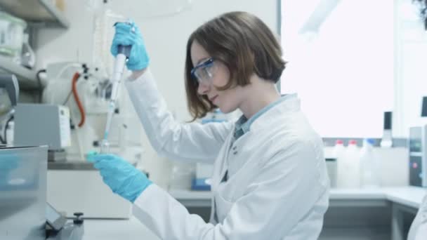 Tým mnohonárodnostní studentů v pláštích pracující v laboratoři chemie učebny. — Stock video