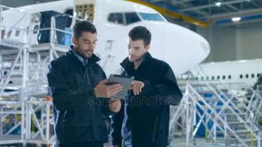 Uçak bakım işçi ve mühendis konuşmayı. Tablet holding.
