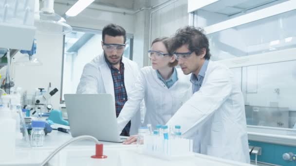 Gruppo di studenti multietnici in cappotti che utilizzano il computer portatile in laboratorio di chimica aula — Video Stock